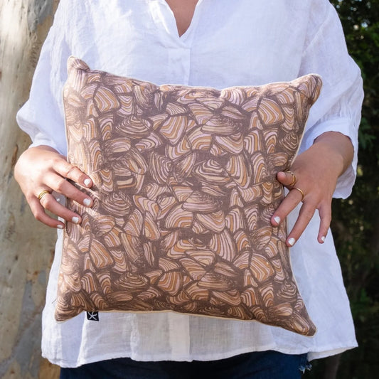 Woman holding square Claytons Pipi linen cushion cover in warm earthy tones