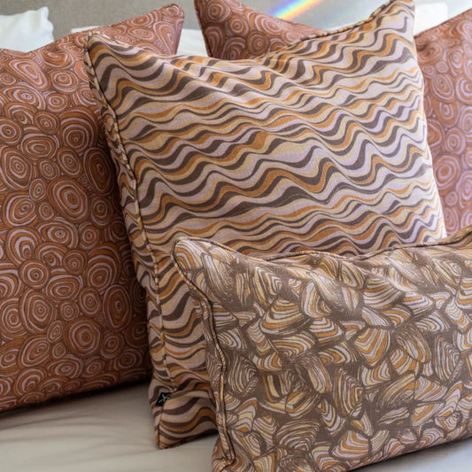 Claytons colourway outdoor indoor cushion covers featuring Pipi, Straddie Stripe and Growth Rings prints styled together on a bed.