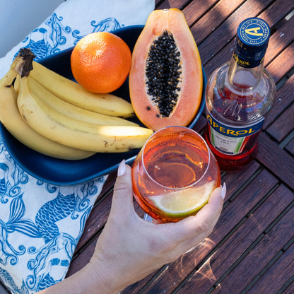 Mermaids Blue linen tea towel styled beside fresh fruit and an Aperol drink on an outdoor table