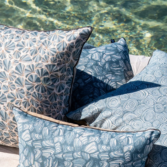 Frenchmans linen cushion covers in Growth Rings, Pipi and Shells patterns styled beside clear coastal water