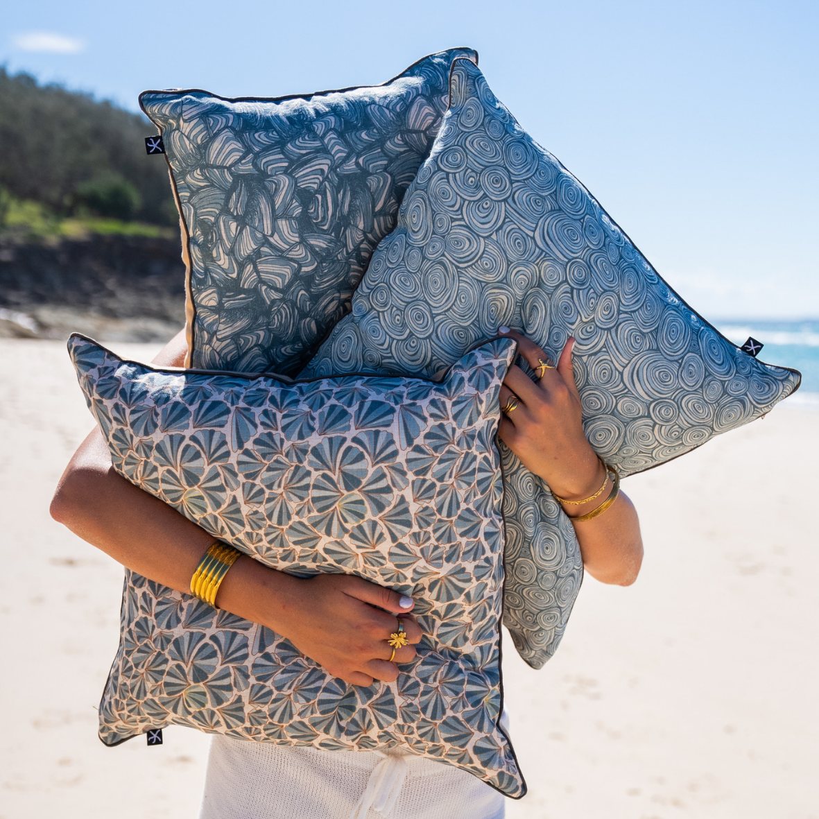 Frenchmans linen cushion collection with Growth Rings, Pipi and Shells designs held together on the beach