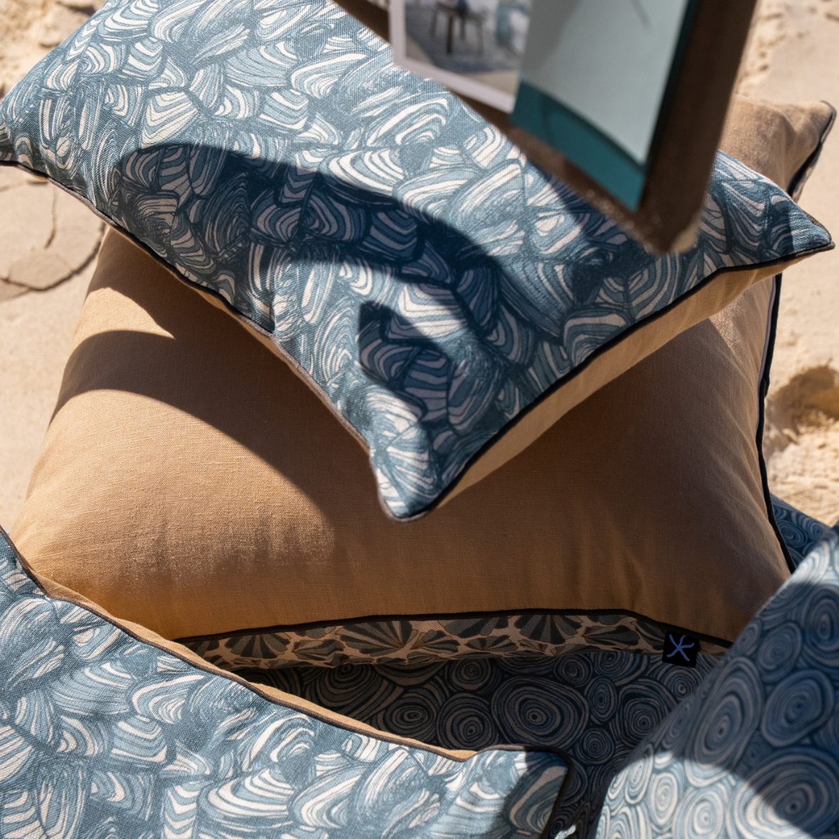 Close-up of stacked linen cushions featuring the Frenchmans Pipi design with a natural linen back.
