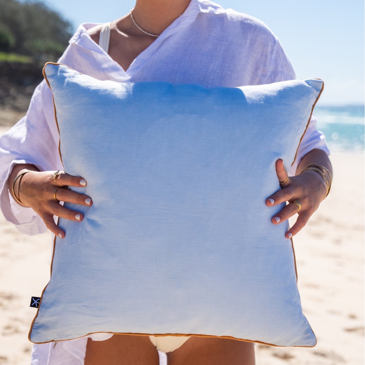 Back of Growth Rings linen cushion cover in plain pale blue fabric with ochre piping