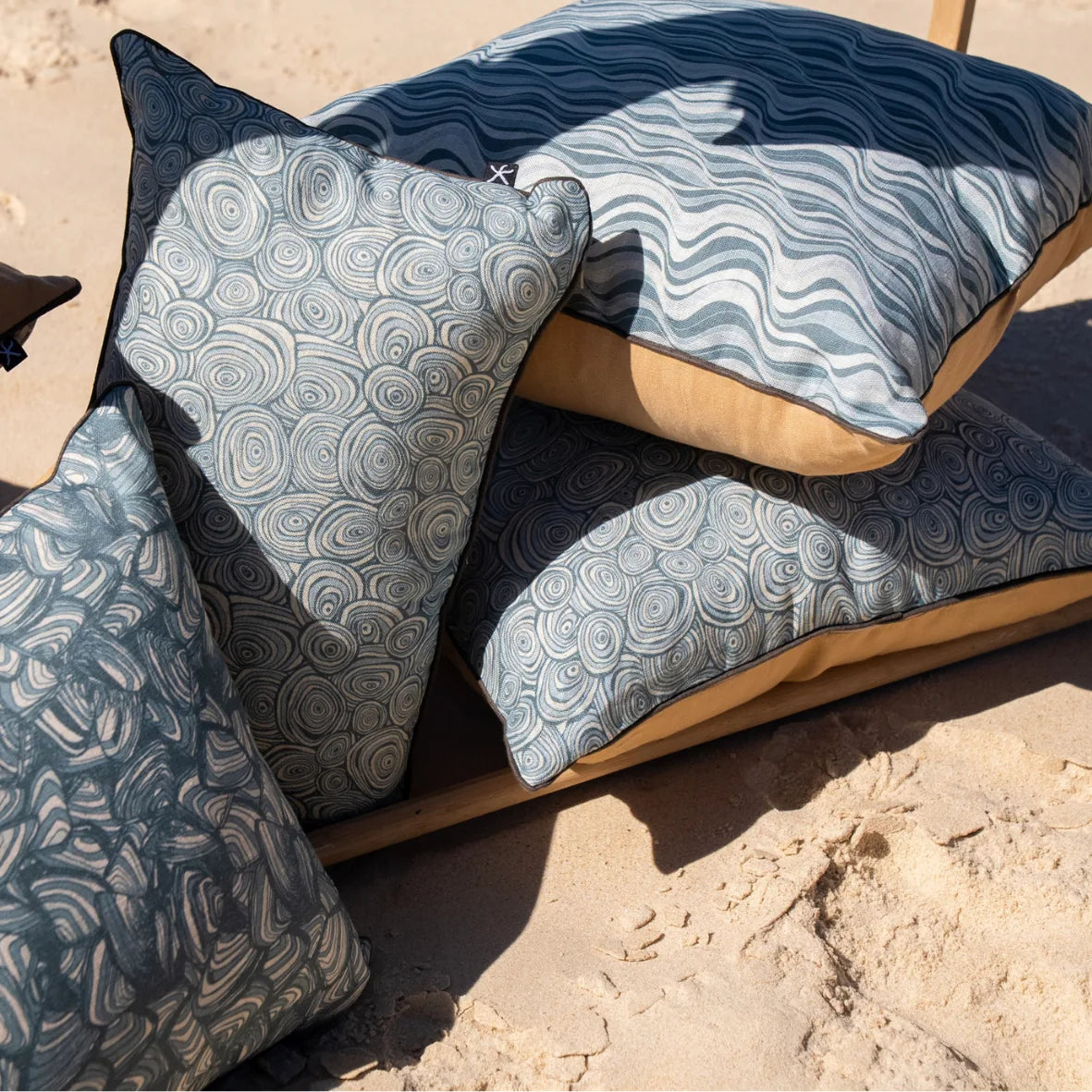 Frenchmans coastal linen cushion collection styled together on the sand, including Straddie Stripe.