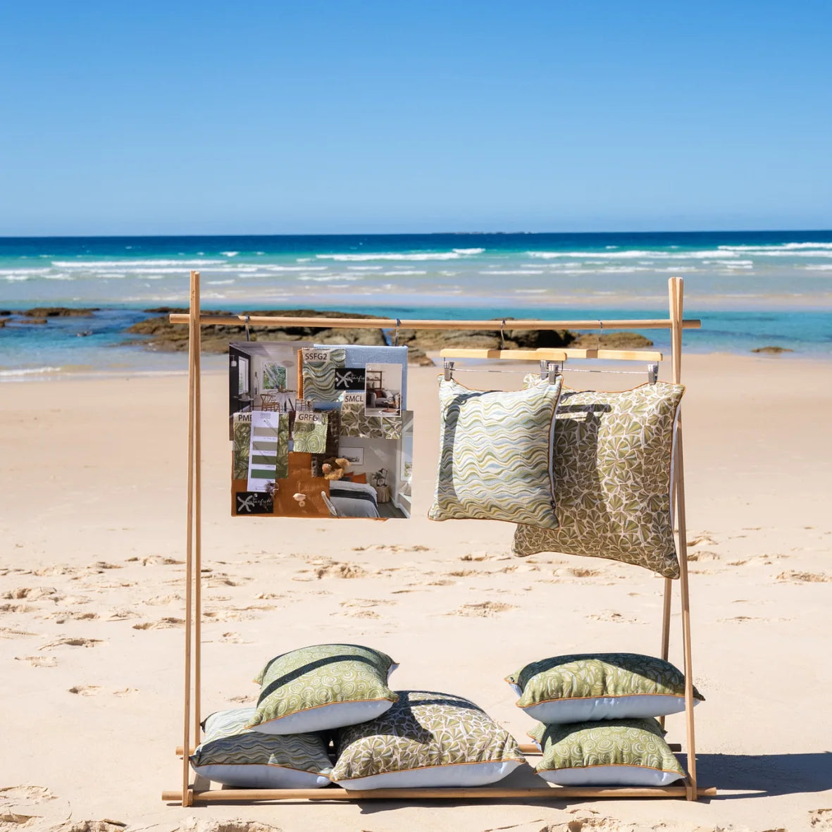 Starfish Studio coastal linen cushion collection displayed on a beach rack, featuring Shells and coordinating green designs.