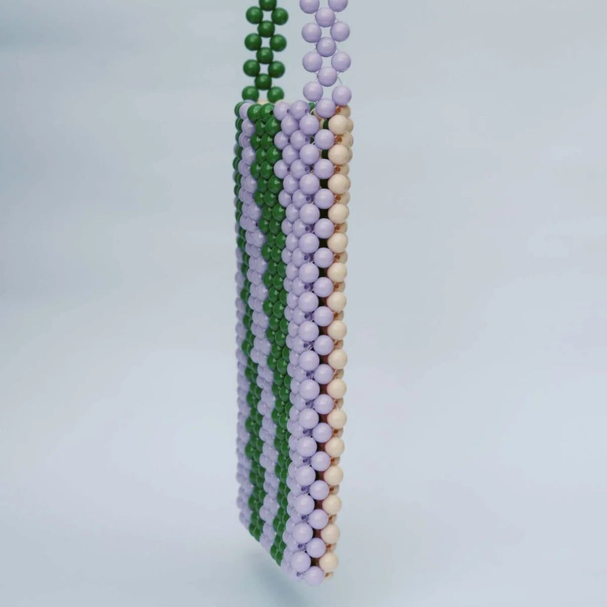 Three beaded necklaces in green, purple, and beige on a light gray background