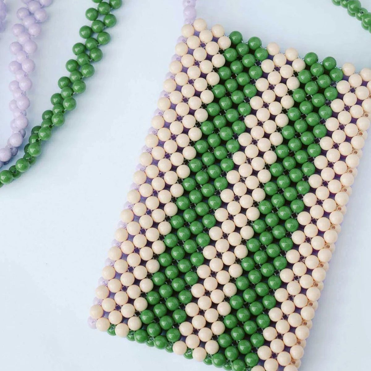 Beaded phone case with green and beige pattern on a white background