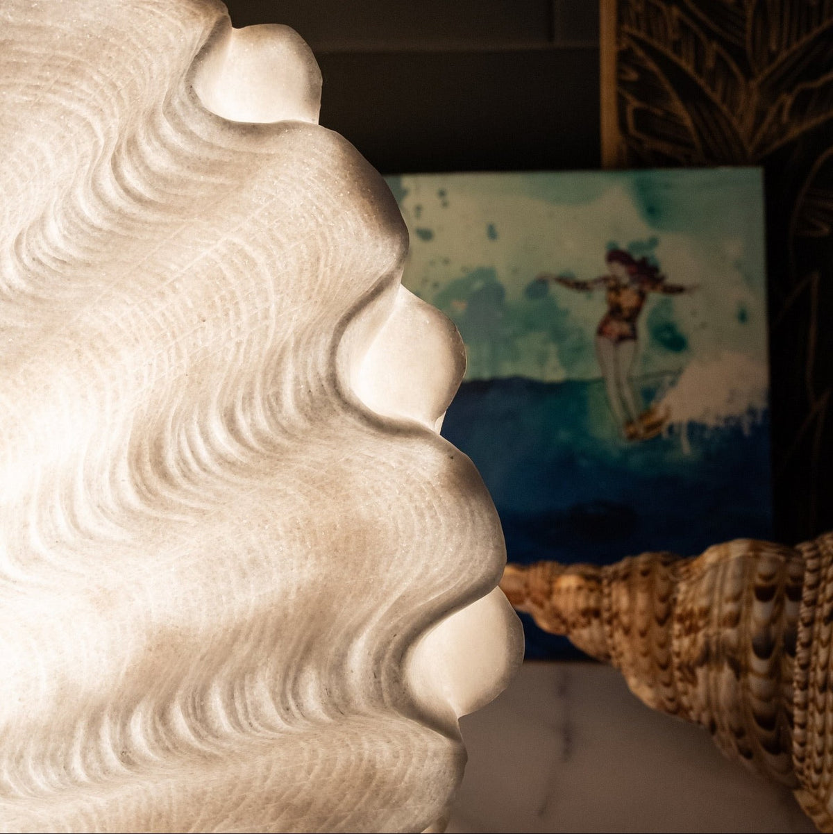 Close-up of the glowing Clam Shell Reef Lamp with coastal artwork and shells