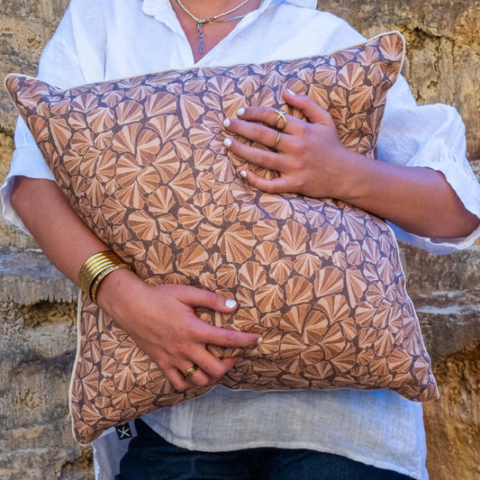 Close-up of Claytons Shells linen cushion cover held in front of sandstone cliffs