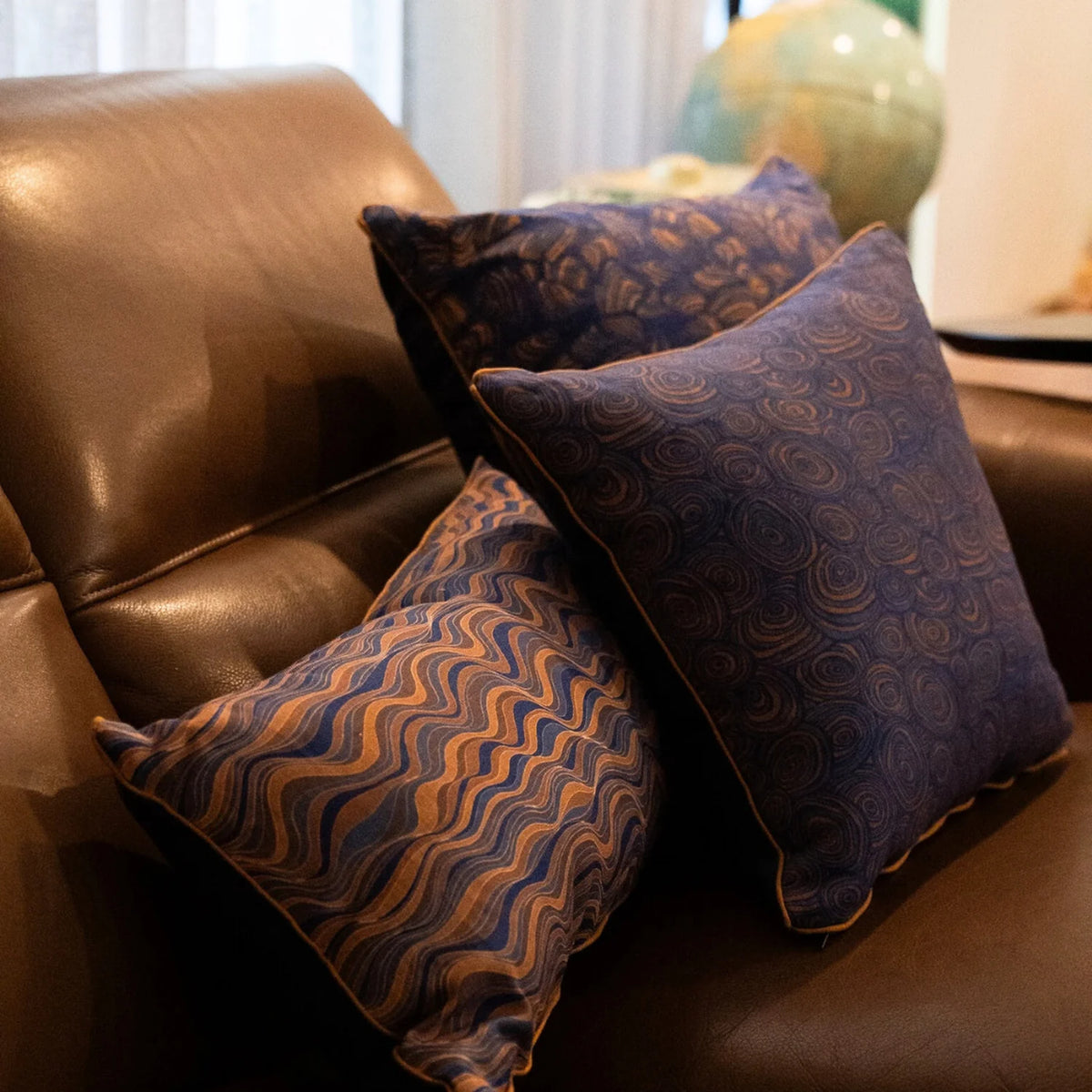 Straddie Stripe Mariner linen cushion cover styled with coordinating navy and ochre cushions on a leather lounge