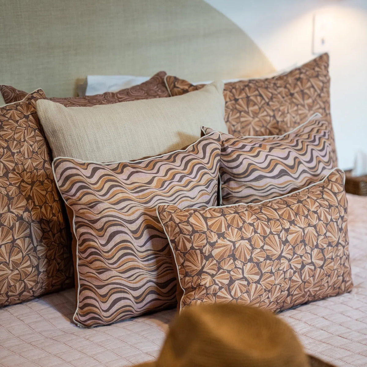 Claytons Straddie Stripe linen cushions styled on a bed with matching Shells cushions