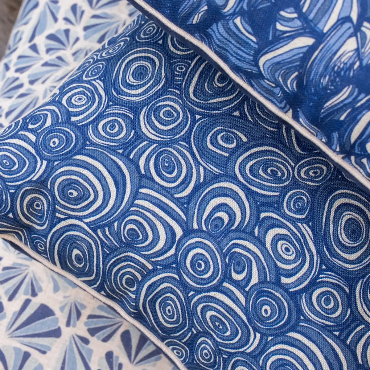 Close-up of Pacific Growth Rings linen cushion cover showing blue circular print and natural piping