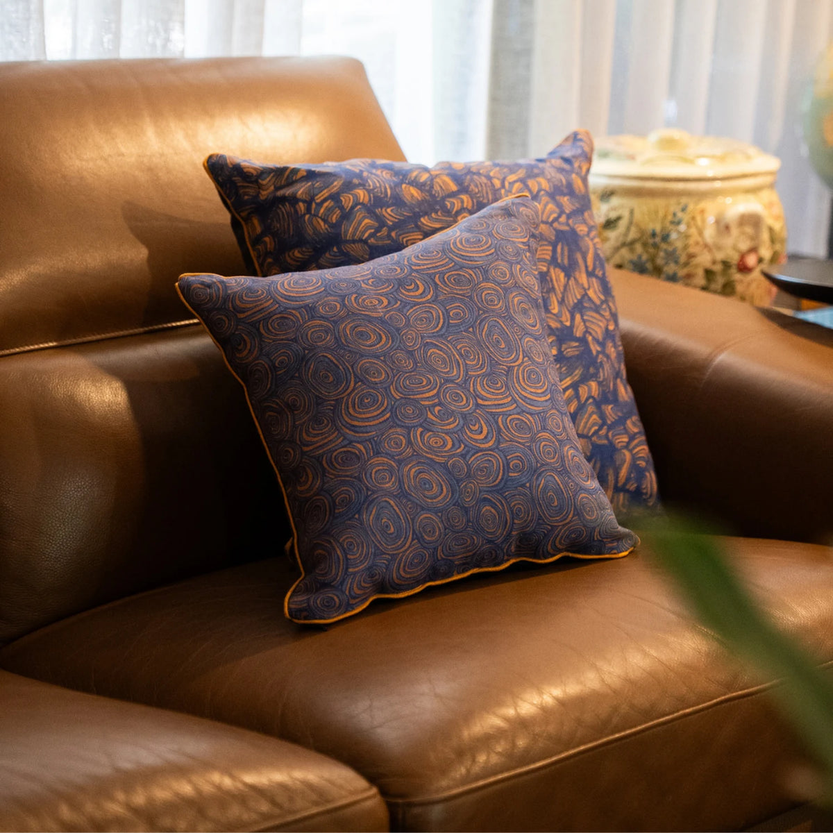 Growth Rings Mariner linen cushion cover styled with coordinating cushions on a leather armchair