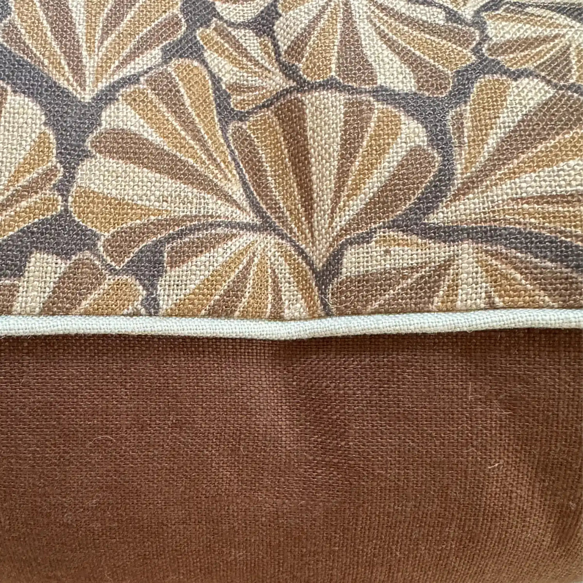 Close-up of Claytons Shells linen cushion cover showing printed fabric, natural piping and warm brown reverse
