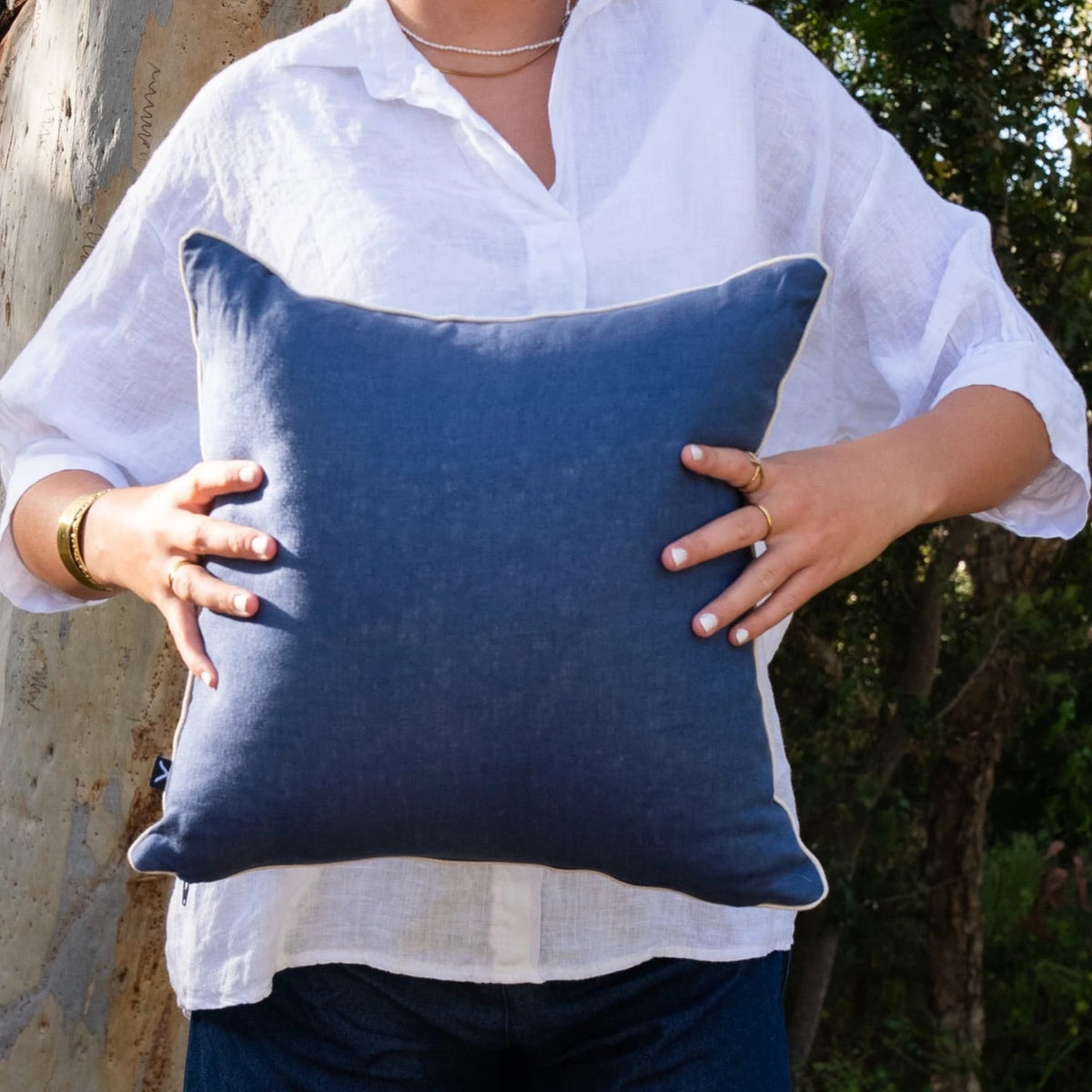 Woman holding navy linen reverse of square Pacific Growth Rings cushion cover