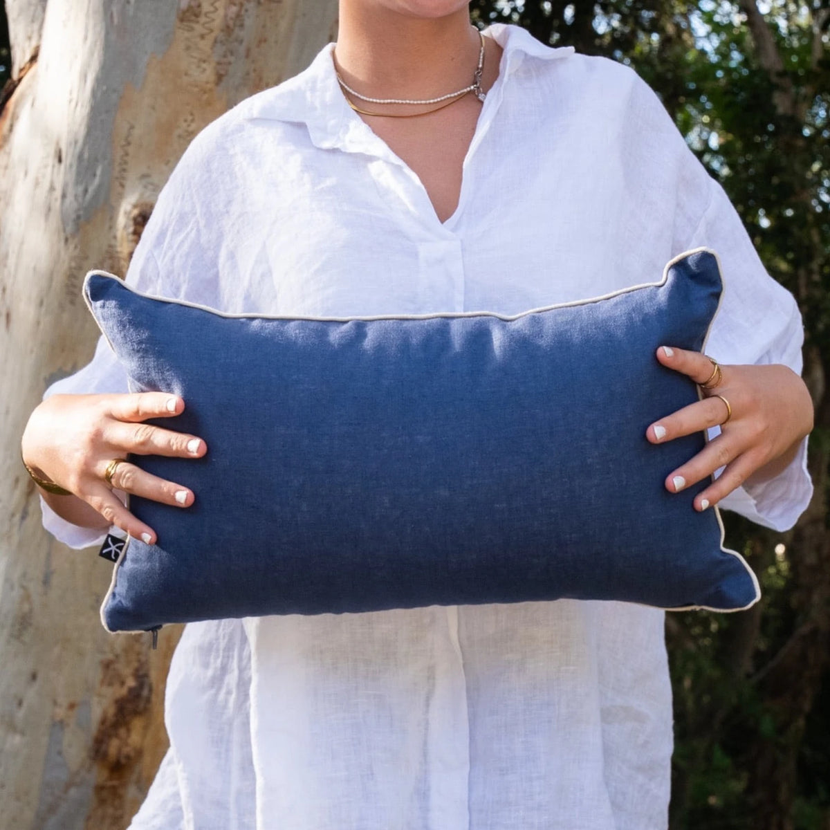 Woman holding navy linen reverse of rectangular Pacific Growth Rings cushion cover