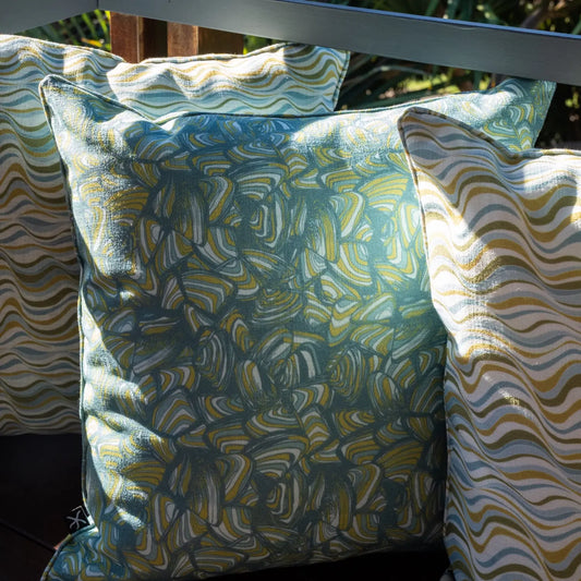 Mangrove Pipi outdoor cushion styled on a timber bench with matching Mangrove cushions in the background.
