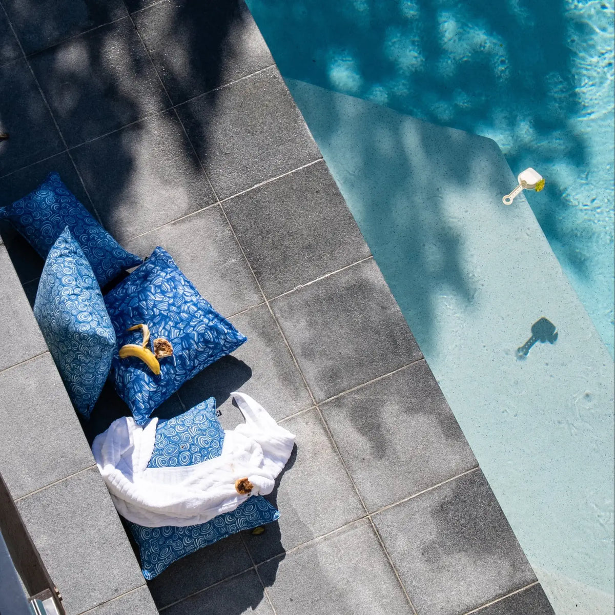 Pacific outdoor cushions styled poolside with a towel, fruit and children’s toys.