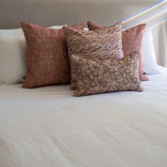 Claytons outdoor indoor cushion covers featuring Straddie Stripe, Growth Rings and Pipi prints arranged on a bed.