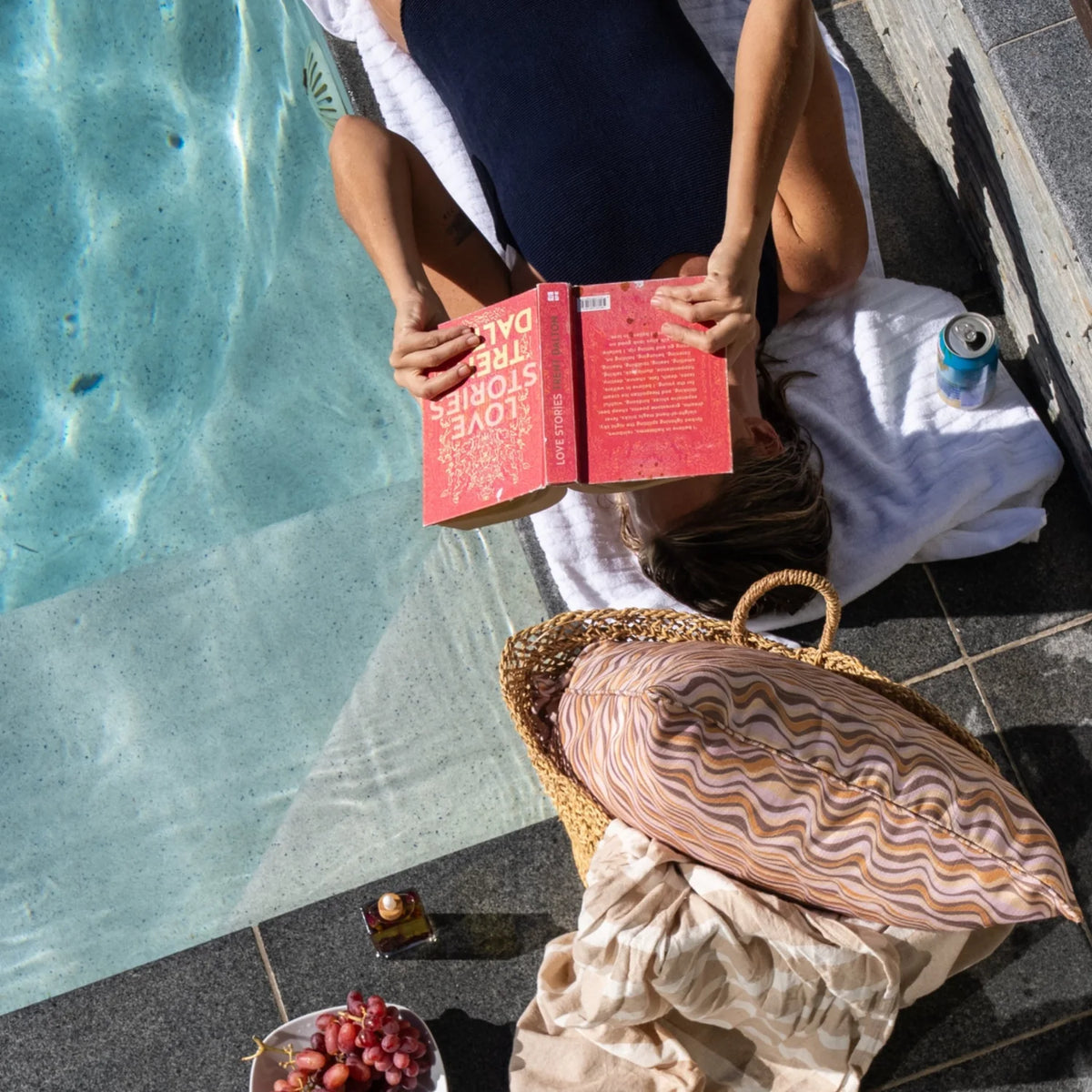 Claytons Straddie Stripe outdoor indoor cushion cover styled in a woven basket beside a swimming pool.
