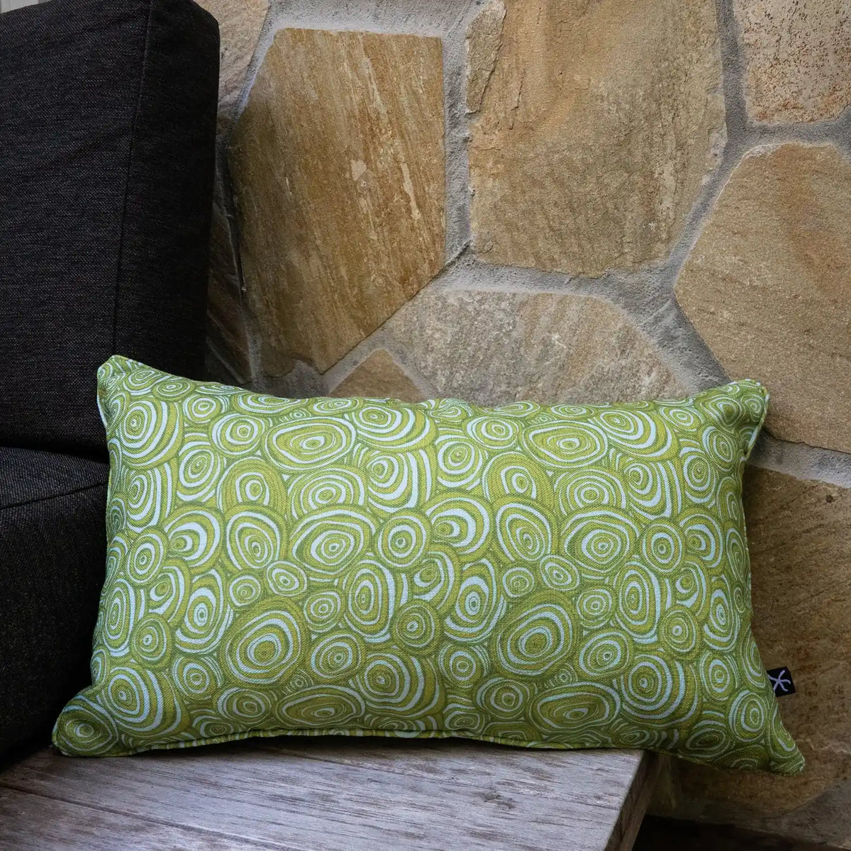 Outdoor Indoor Growth Rings cushion cover in Mangrove, rectangular lumbar size, on a stone wall bench