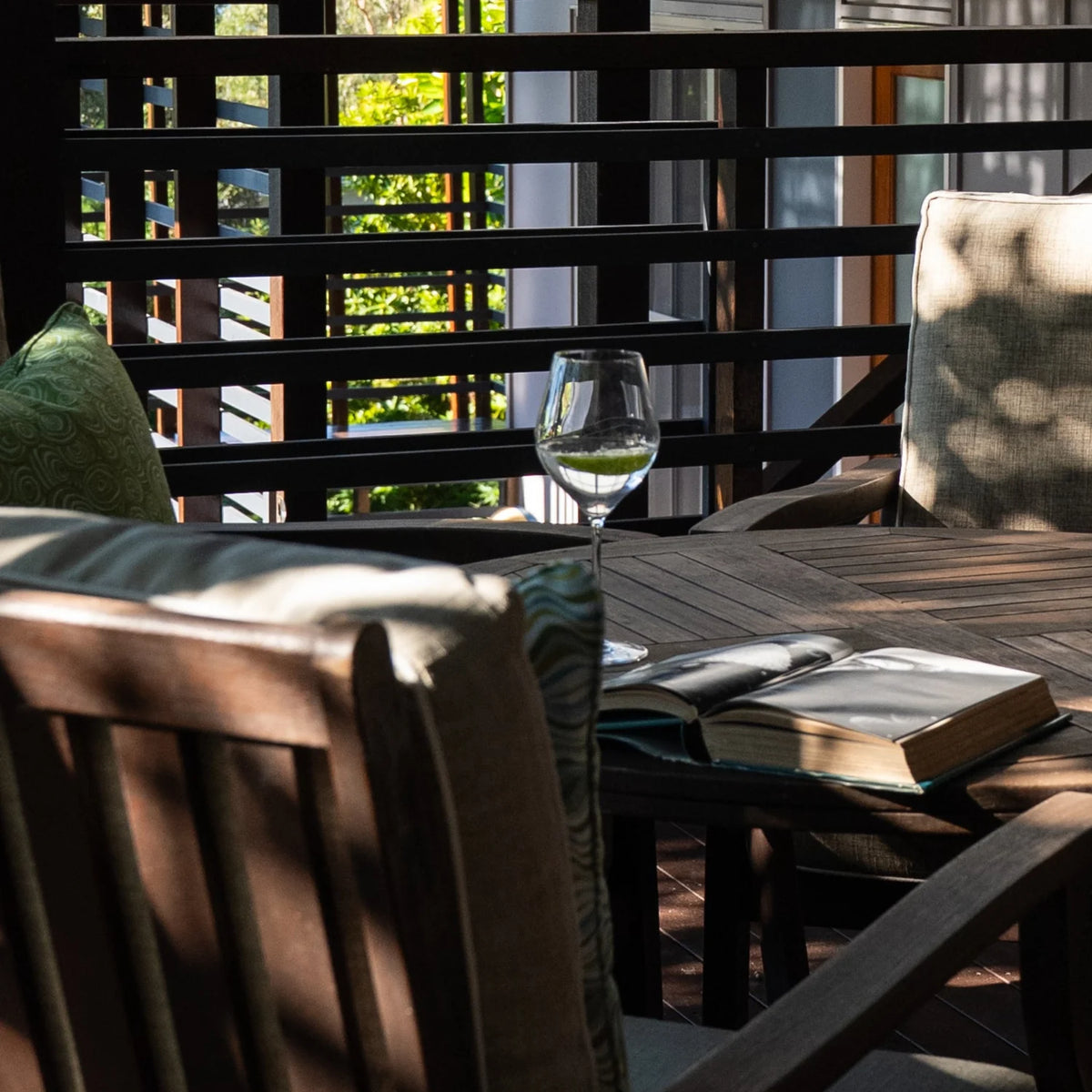 Outdoor Indoor Growth Rings cushion cover in Mangrove on an outdoor entertaining chair with wine and a book