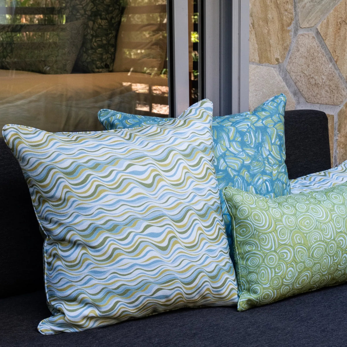 Mangrove colourway outdoor indoor cushion covers featuring Straddie Stripe, Pipi and Growth Rings prints styled together on a lounge.